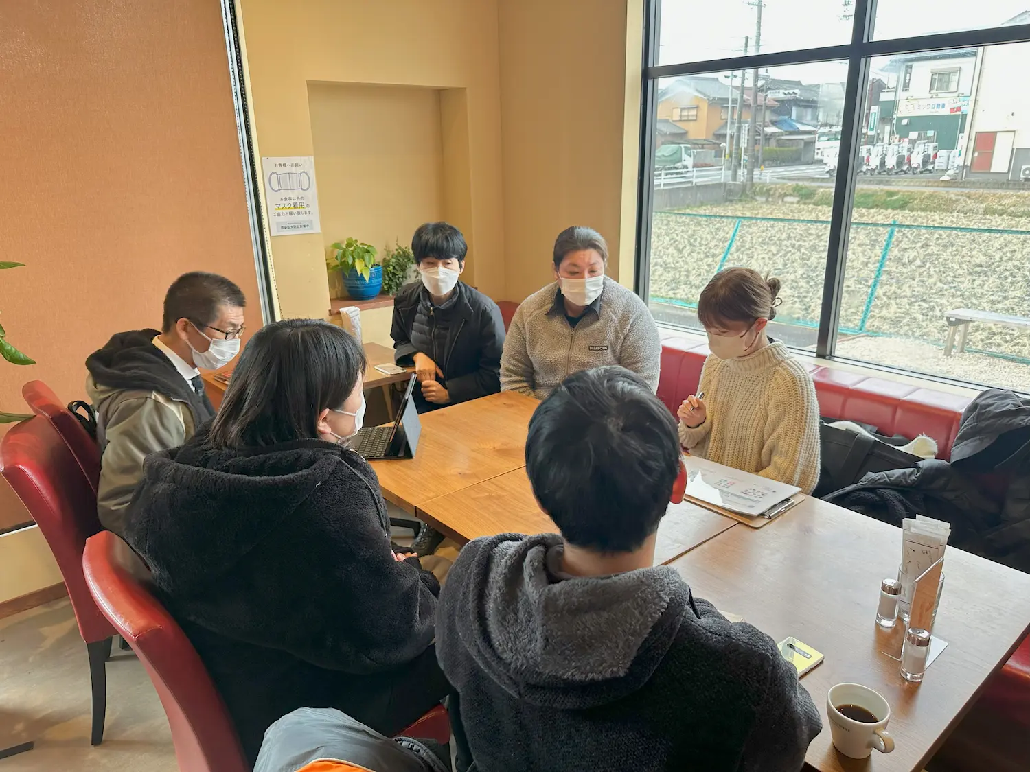 机の周りに座って話をする男女6人