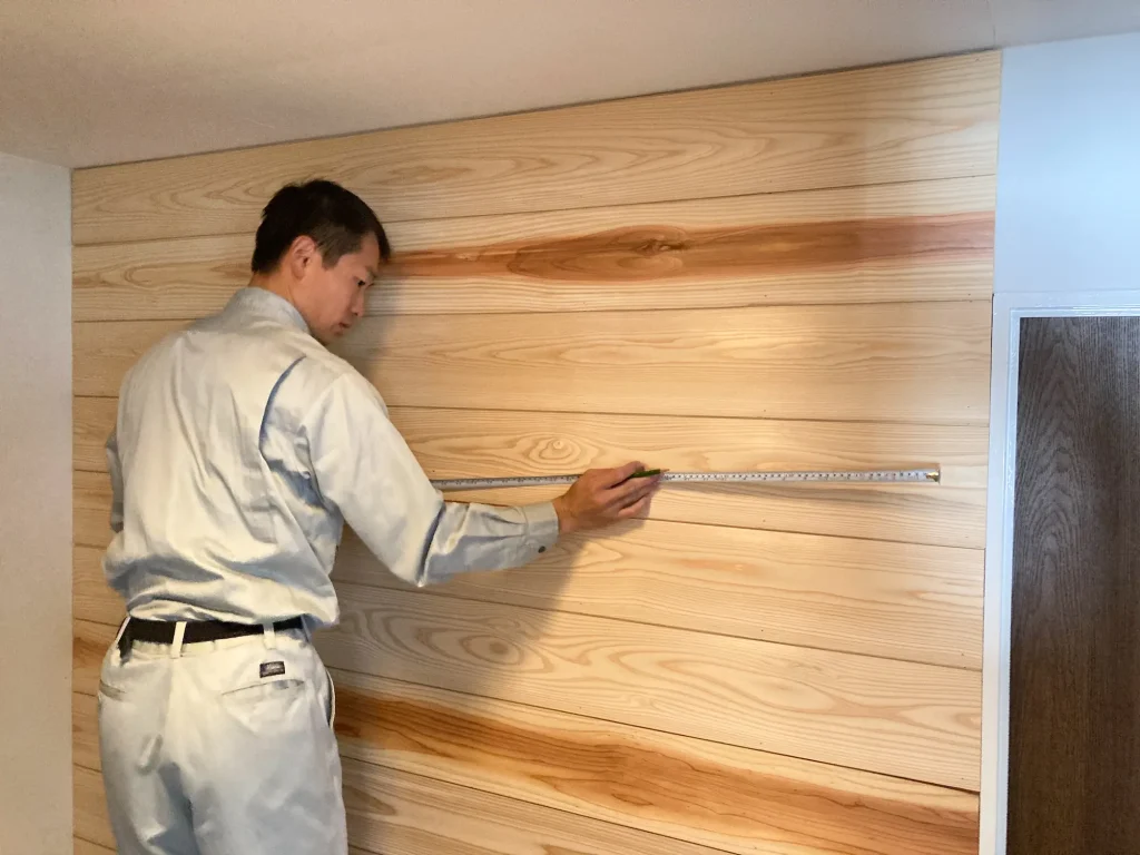 メジャーを使って壁を点検している男性