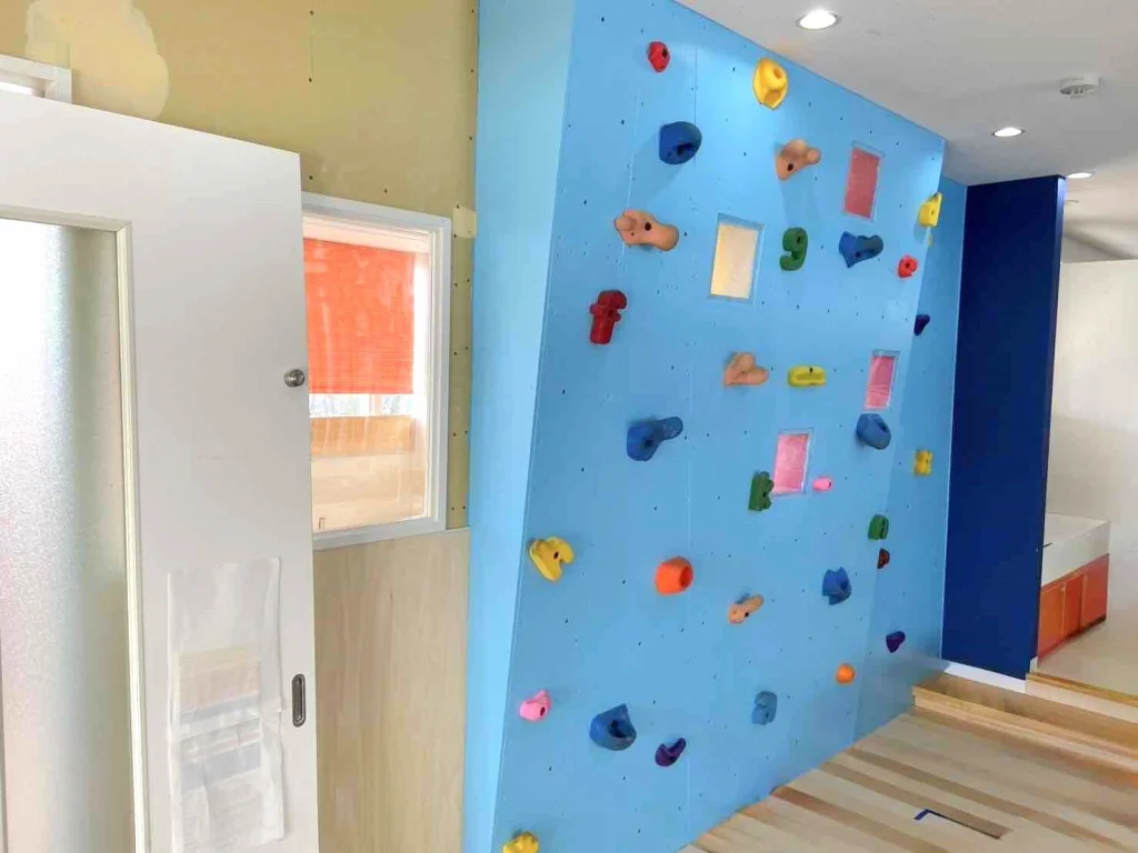 水色のボルダリングの壁がある室内。