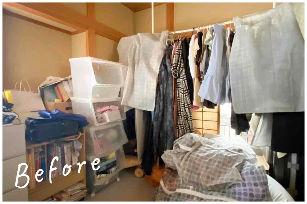 物がたくさんある部屋。洗濯物が干され、本棚やアクリルケースにたくさんのものが収納されている