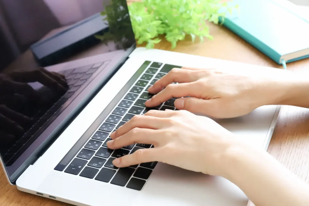 ノートパソコンでタイピングする様子