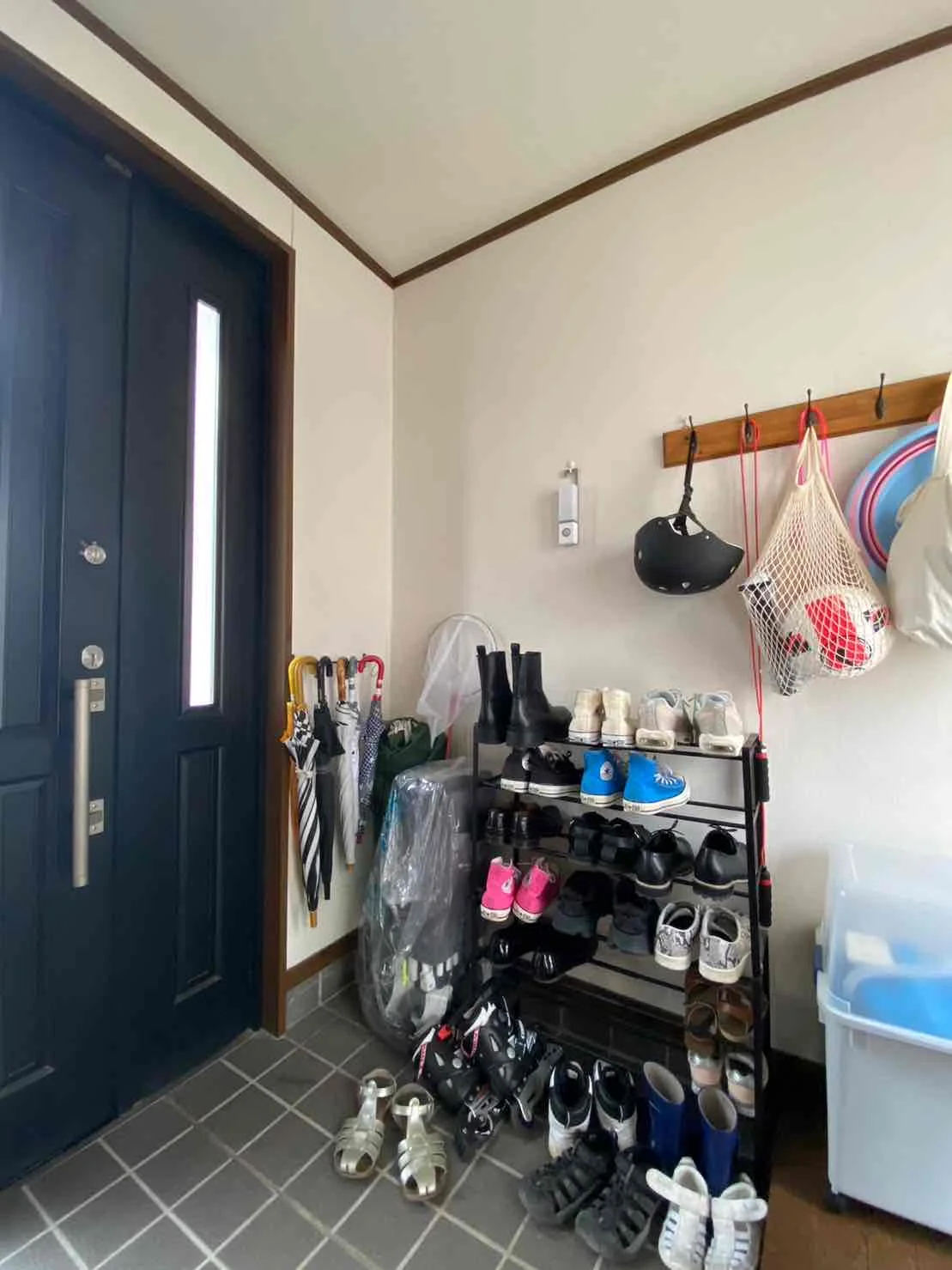 リフォーム前の玄関の様子。靴用の棚に靴が置かれ、壁には傘やヘルメットがかけられている。