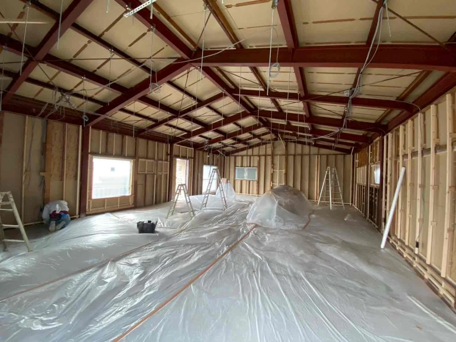リフォーム中の室内。建物の骨組みが見えていて、床にはシートが貼られている。
