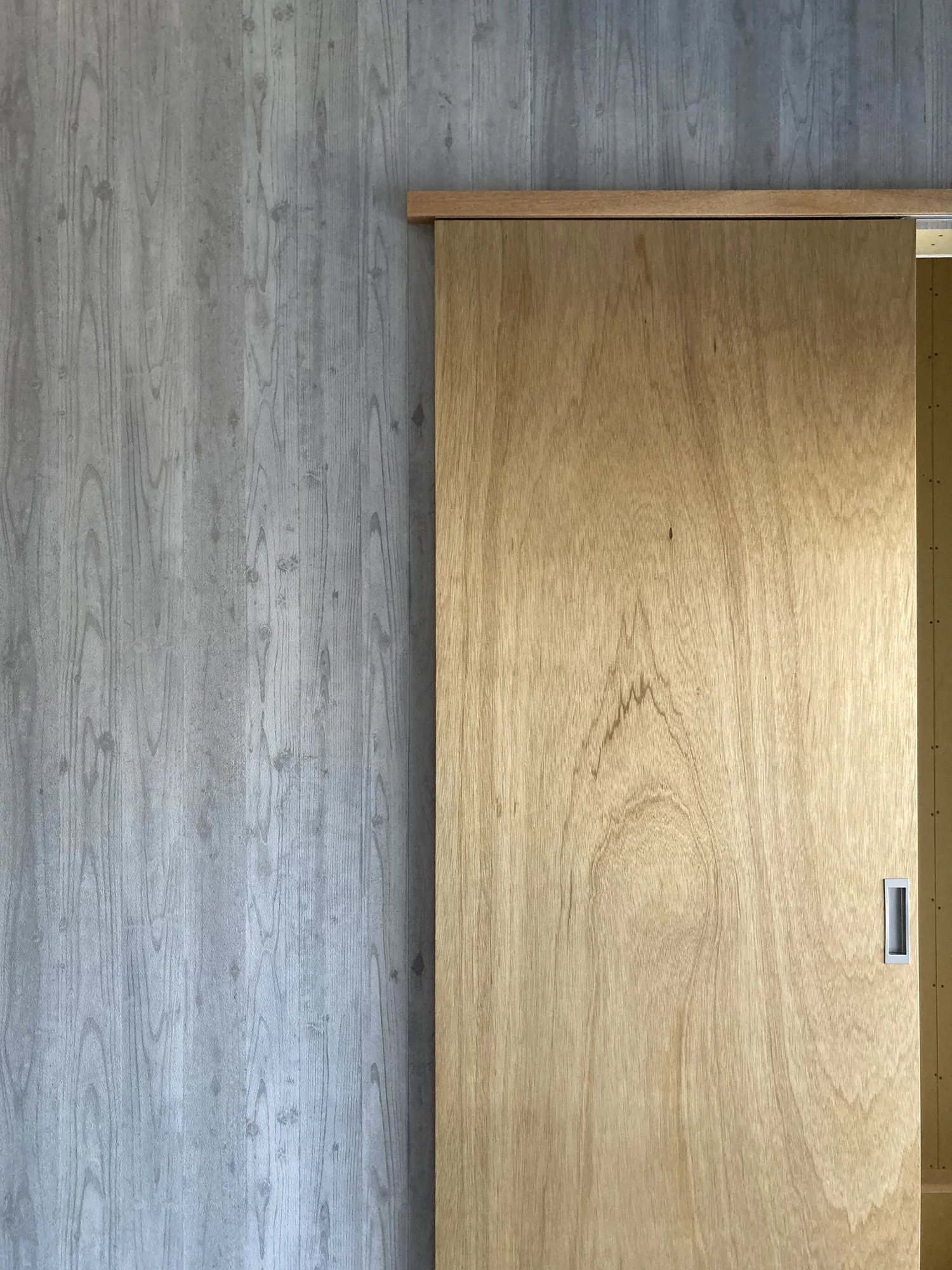 引き戸のある部屋の入口。灰色で木目の壁と薄茶色の木の引き戸。