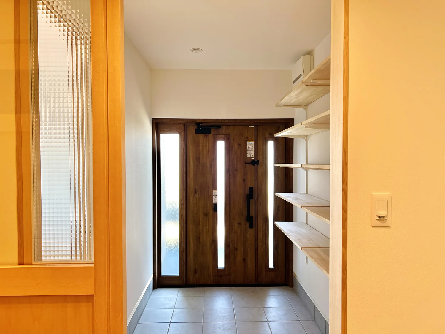 リフォーム後の玄関。大きな棚が壁に設置されていて、明るい雰囲気。