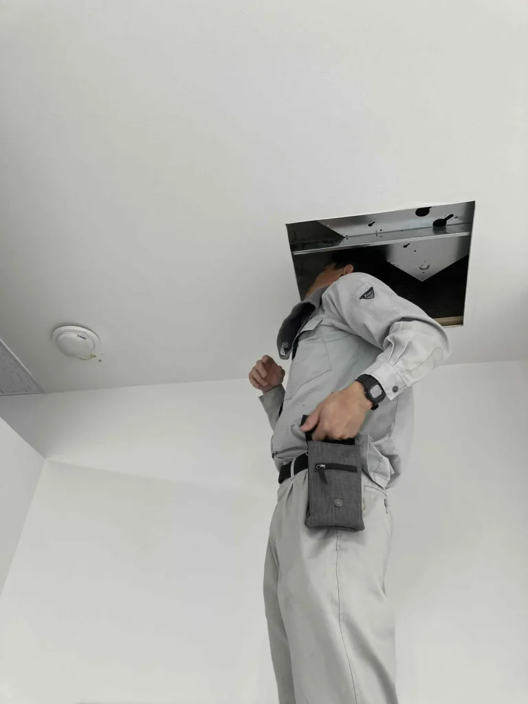 天井を開けて覗き込み、屋根裏の点検をする男性